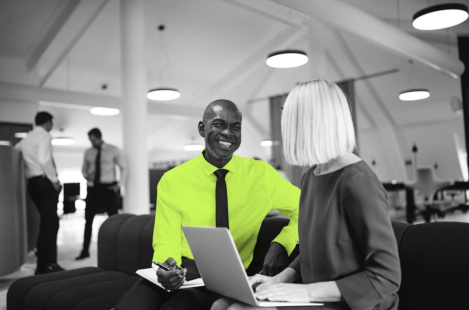 man and woman talking and laughing with open laptop